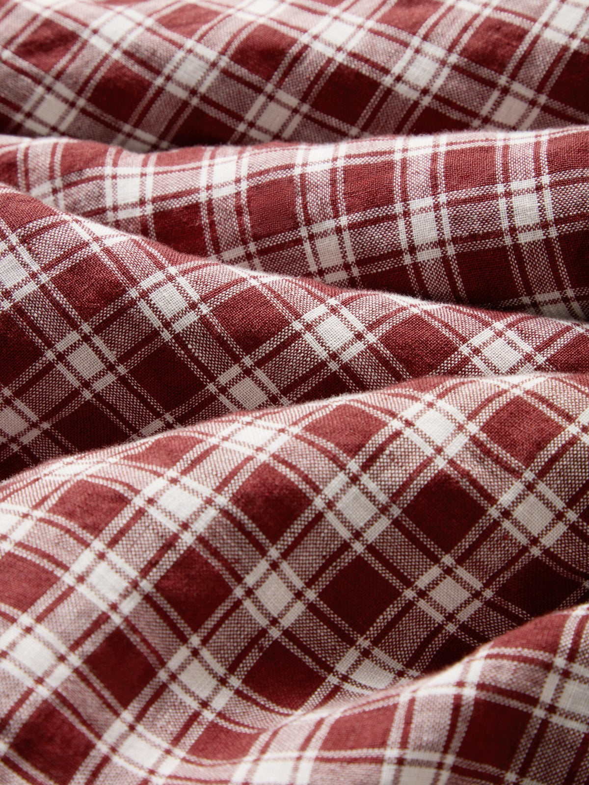A close-up of draped red and white plaid fabric, showing the woven texture and pattern details.