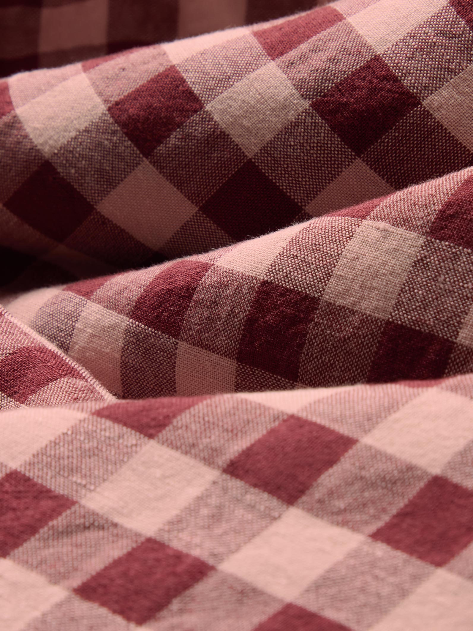 A close-up of draped fabric with a red and beige gingham plaid pattern.