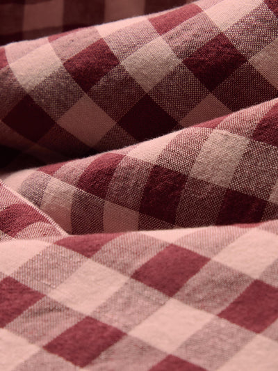A close-up of draped fabric with a red and beige gingham plaid pattern.