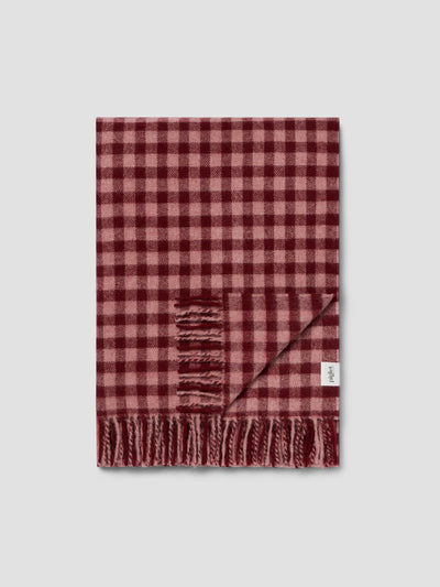 A red and pink gingham blanket on a light grey background