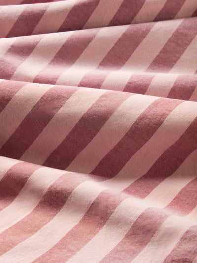 A close-up of draped fabric with alternating diagonal stripes in dusty rose pink and off-white.