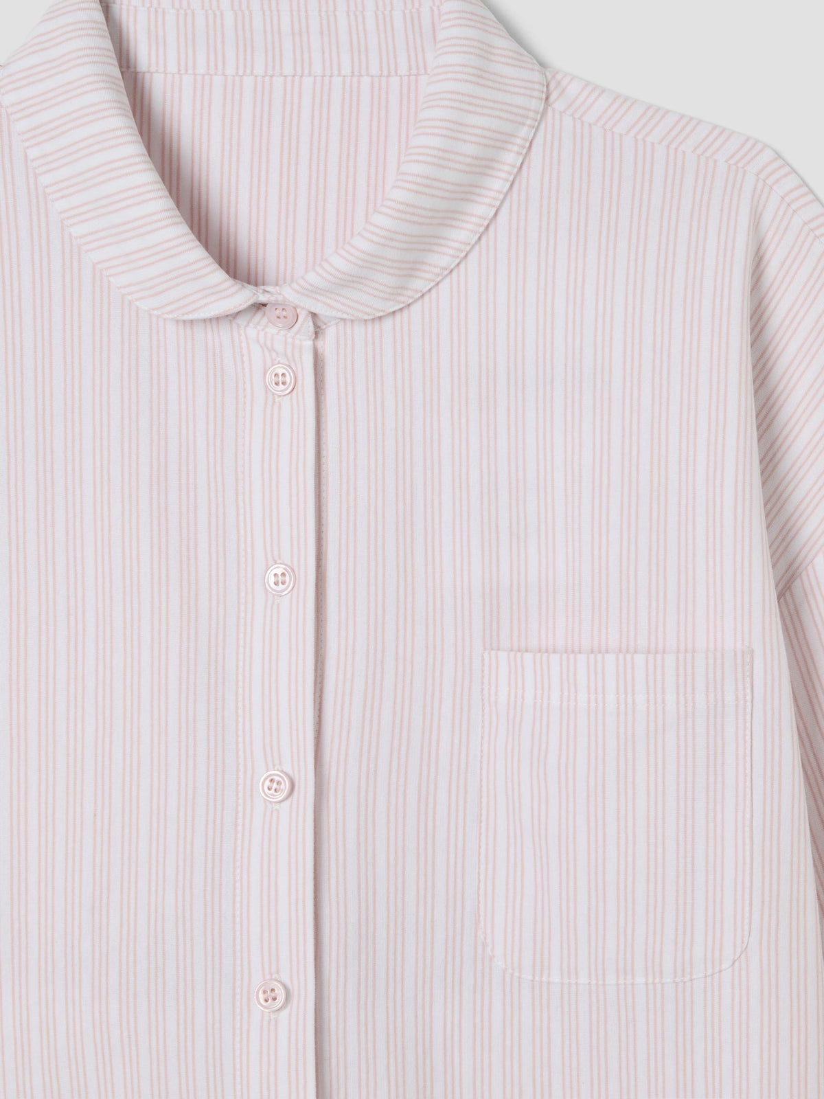 A close-up of a long-sleeve button-up shirt with a Peter Pan collar and a chest pocket, featuring a fine vertical stripe pattern in light pink and white.