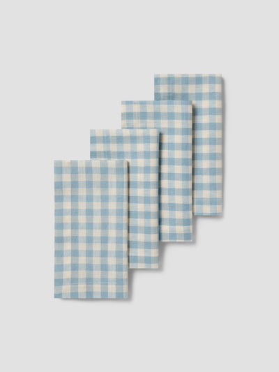 Set of four blue and white checkered napkins on a light gray background