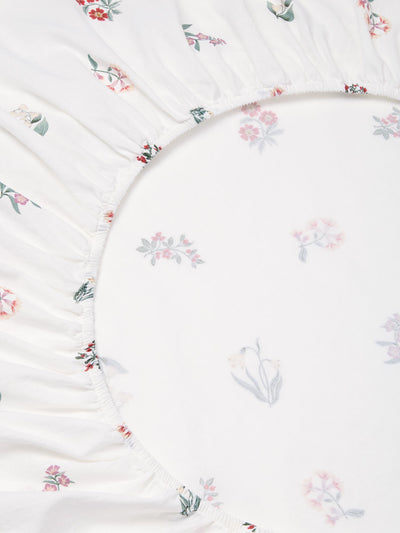 Close up of white fitted sheet with a subtle floral print. 
